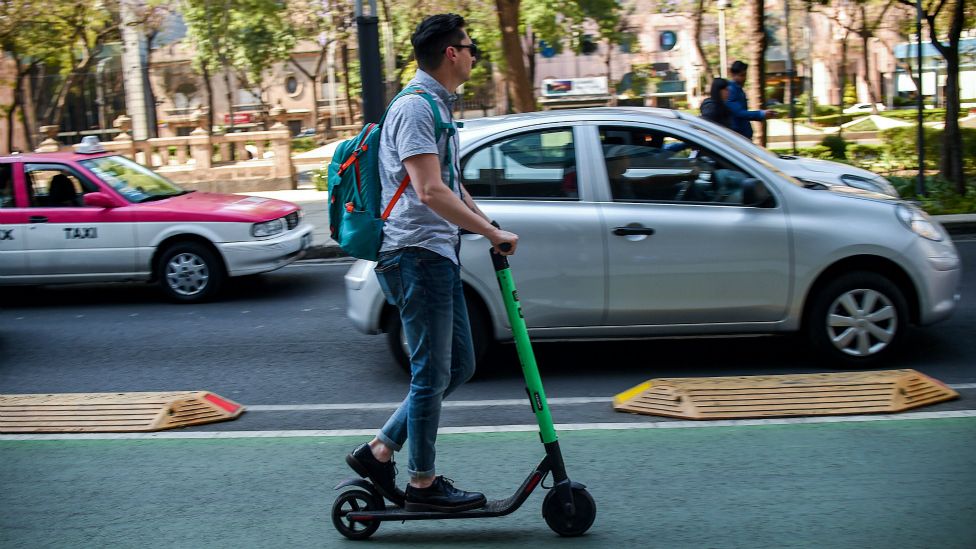 Un hombre transportándose en un scooter.