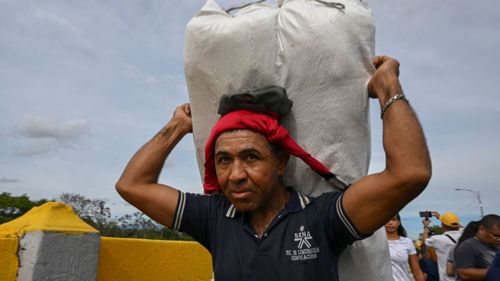 Un hombre caqrga mercancía sobre su espalda en el cruce fronterizo entre Colombia y Venezuela