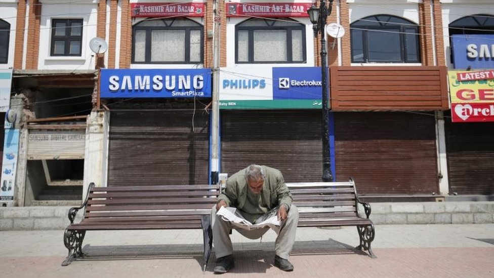 Мужчина читает газету перед закрытым рынком во время остановки работы в Сринагаре, летней столице индийского Кашмира, 12 апреля 2016 года.