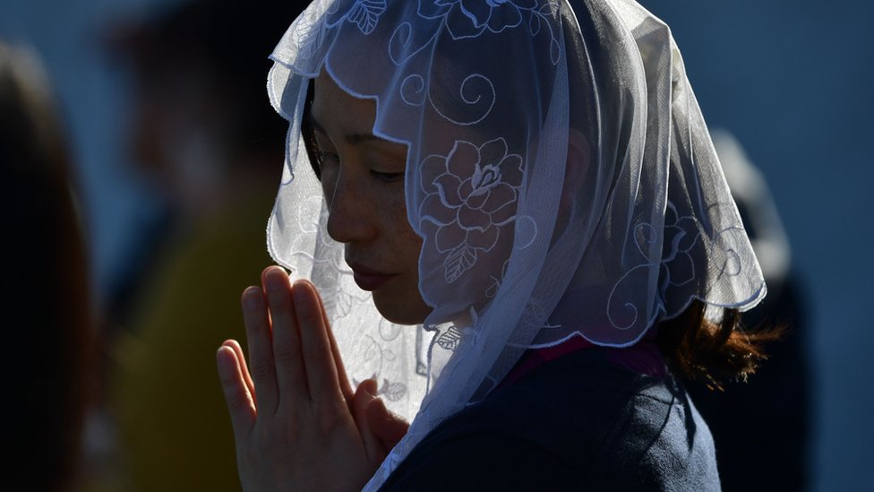 Женщина посещает Святую Мессу Папы Франциска на бейсбольном стадионе в Нагасаки