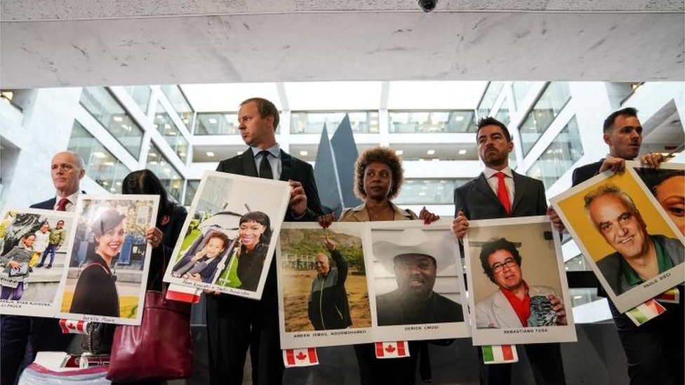 Члены семей держат фотографии жертв авиакатастрофы Boeing 737 MAX, погибших в двух смертельных авариях 737 MAX