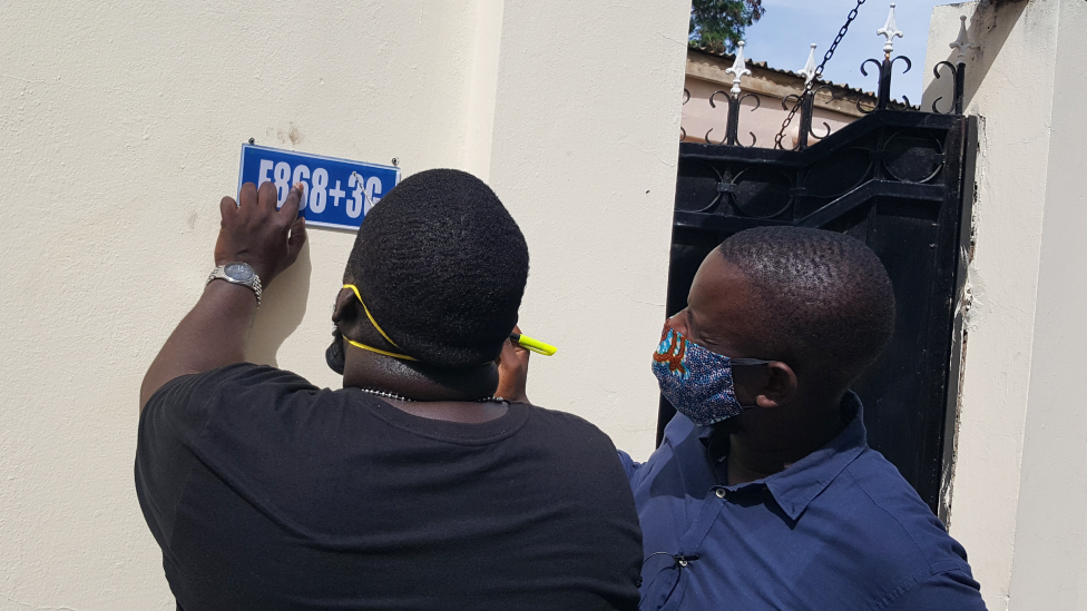 Bakary Suso (L) and Alieu Sowe, (R) putting a plus code sign on a house in The Gambia