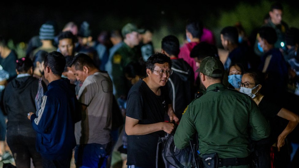 Chinese migrants speak to a border patrol officer before being processed after they crossed the Rio Grande into the U.S. on May 05, 2022 in Roma, Texas.