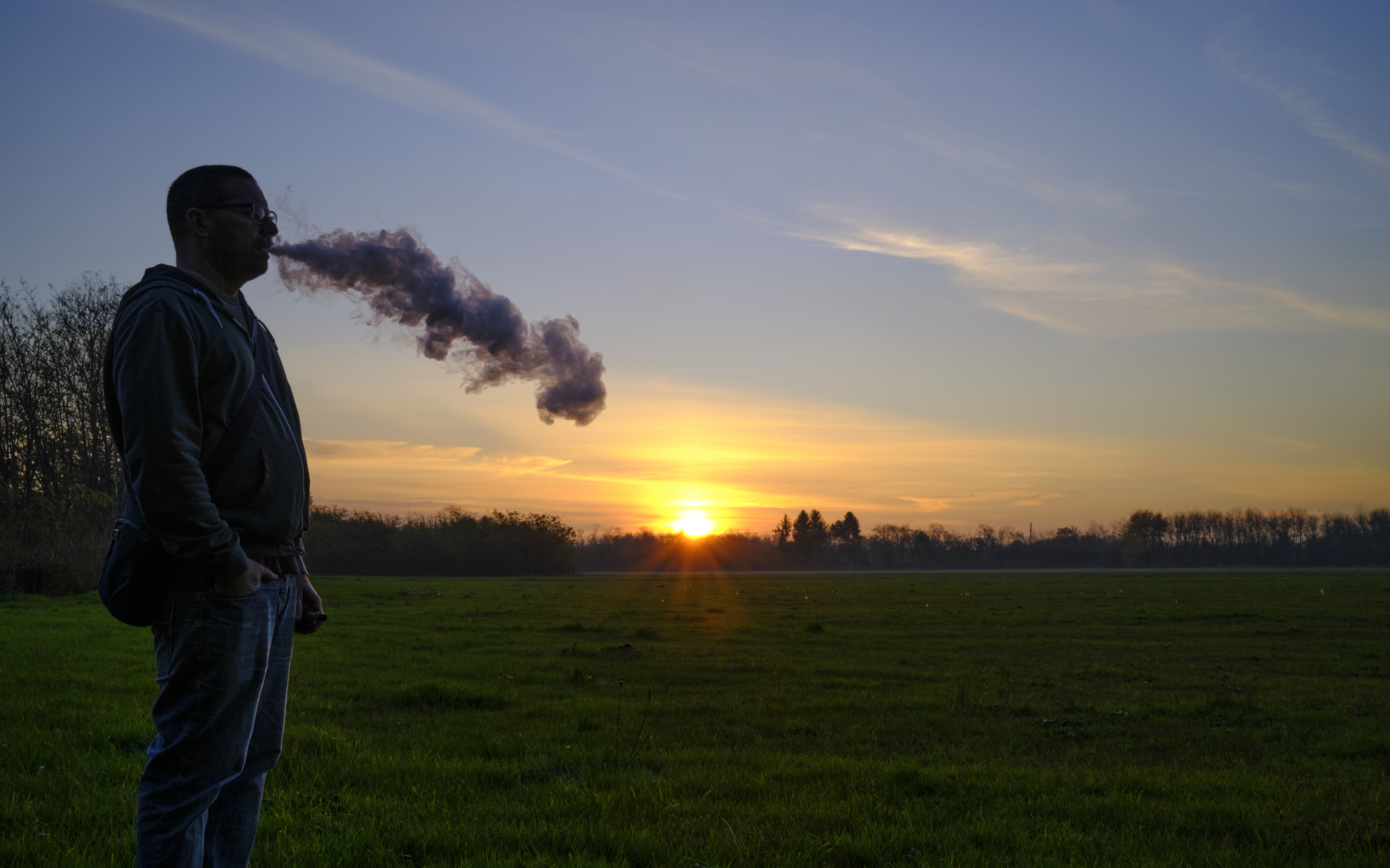 A man smokes during sunset
