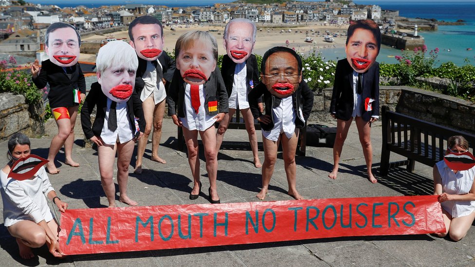 英國康沃爾郡聖艾夫鎮一群示威者扮演與會各國領導人並拉開「光張嘴吧不穿褲子」標語（13/6/2021）