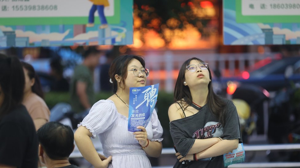 Job seekers are looking for information at a night market recruitment fair in Sanmenxia, China, on August 16, 2024. (Photo by Costfoto/NurPhoto via Getty Images)