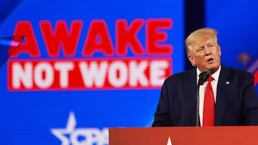 Donald Trump en la última Conferencia de Acción Política Conservadora (CPAC) en febrero de 2022, con un cartel atrás que dice: "Despierto, no woke".