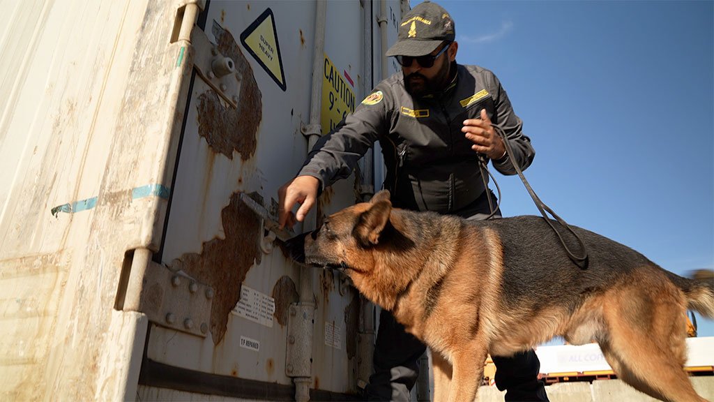 Un policía con un perro detectando drogas.