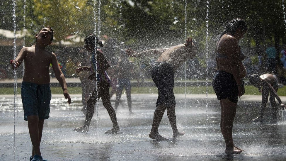 People cool off in water fountains in Madrid on June 26, 2019 at the start of a heatwave