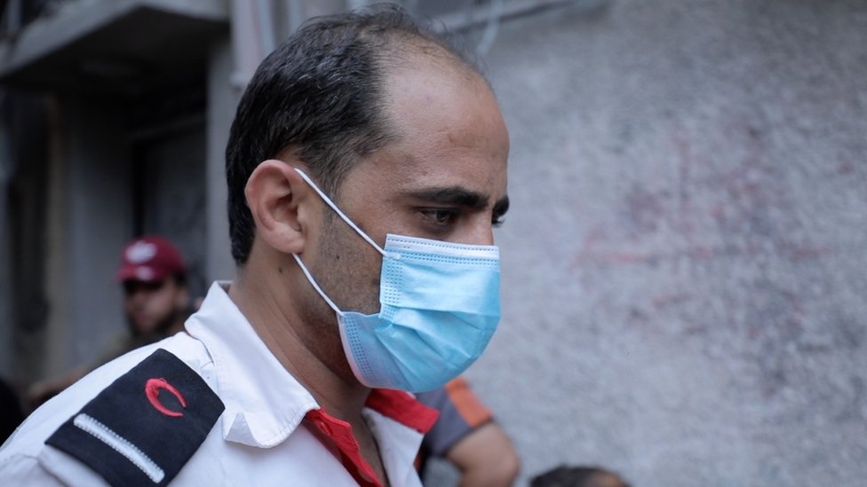 Alaa, pictured in a medical mask, helping collect bodies from his uncle's house, 27 October 2023