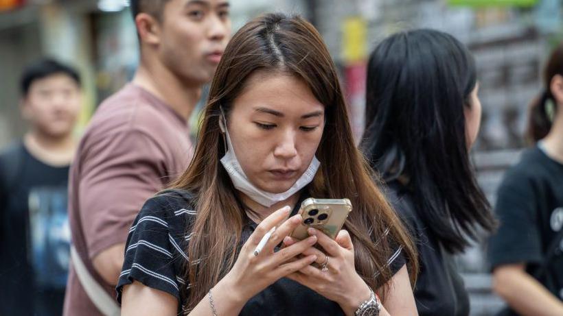 A woman looks at her phone in Hong Kong after new national security rules expanded police powers.
