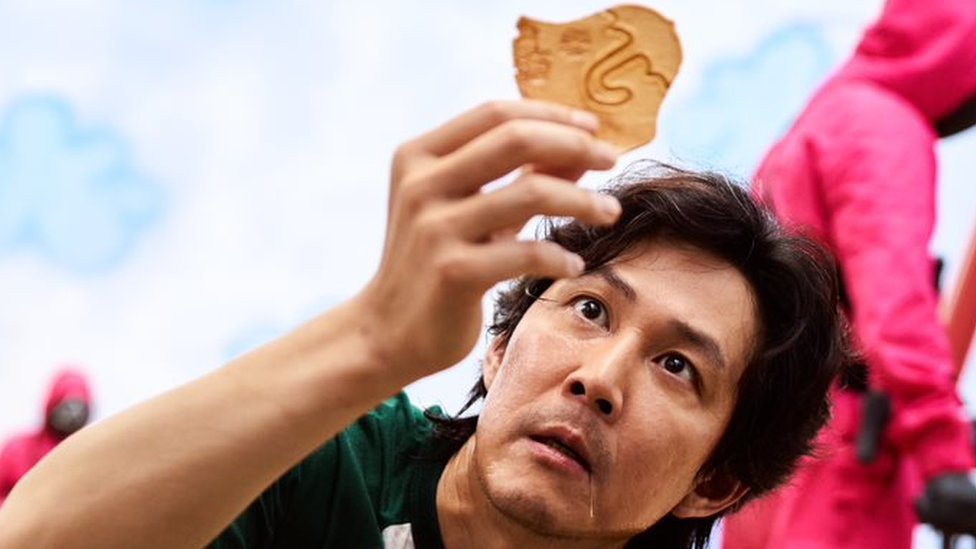 Seong Gi-hun, uno de los personajes principales de "El juego del calamar", sostiene una dalgona.