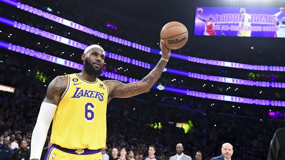 Lebron James holding a basketball in the air after breaking the NBA scoring record
