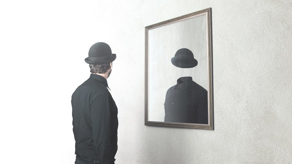 Foto conceptual de un señor mirándose al espejo, en su reflejo no hay rostro.