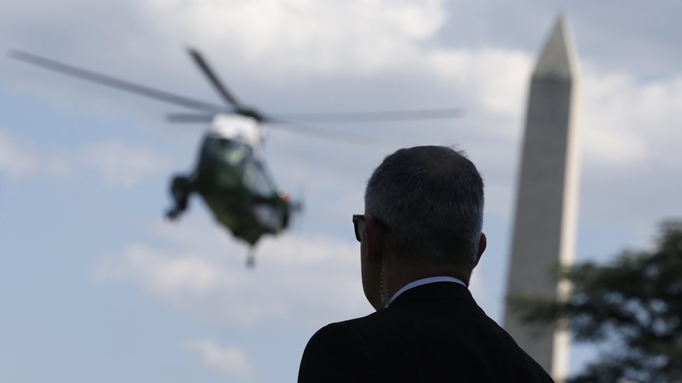 Агент Секретной службы США наблюдает за прибытием вертолета Marine One, чтобы забрать президента Дональда Трампа, который проведет выходные в его гольф-клубе в Нью-Джерси с южной лужайки Белого дома в Вашингтоне, США, 9 июня 201 г.