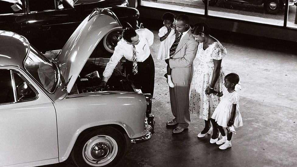 Семья из Гайаны демонстрирует автомобиль Morris в выставочном зале, 1958 год.