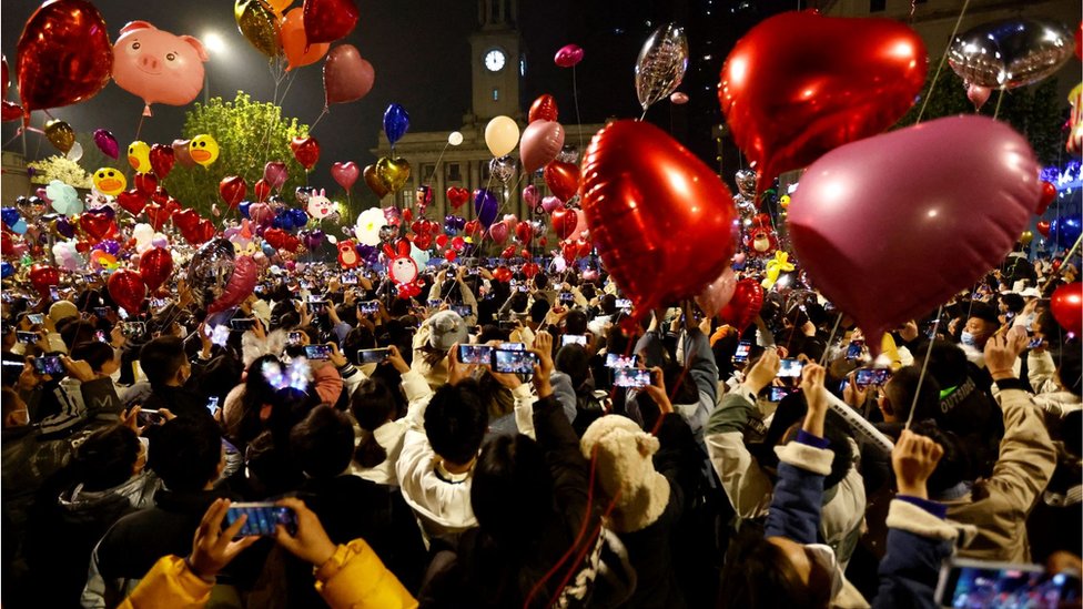 Orang-orang di Wuhan, China, melepaskan balon saat berkumpul untuk merayakan tahun baru di tengah lonjakan kasus Covid-19 di negara itu.