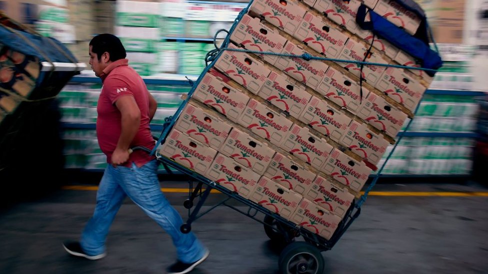 Hombre cargando cajas en el mercado de abastos en Ciudad de México