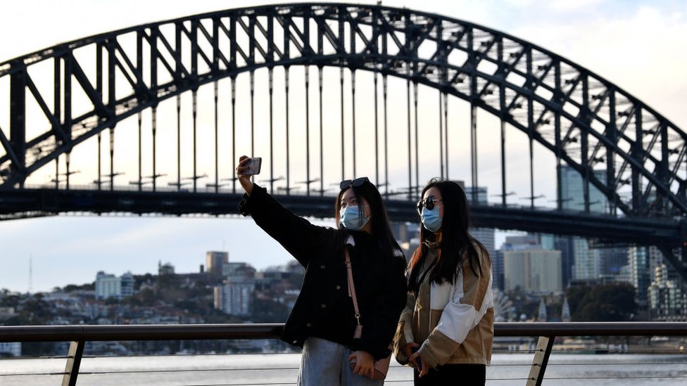 Chinese people wearing masks take a selfie in front of the Sydney Harbour Bridge