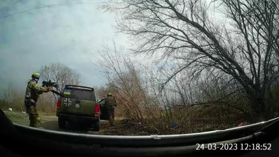 Staged video claims to show Ukrainian soldiers abusing civilians; the image shows a car with a flag of Ukraine and soldiers stepping out of it