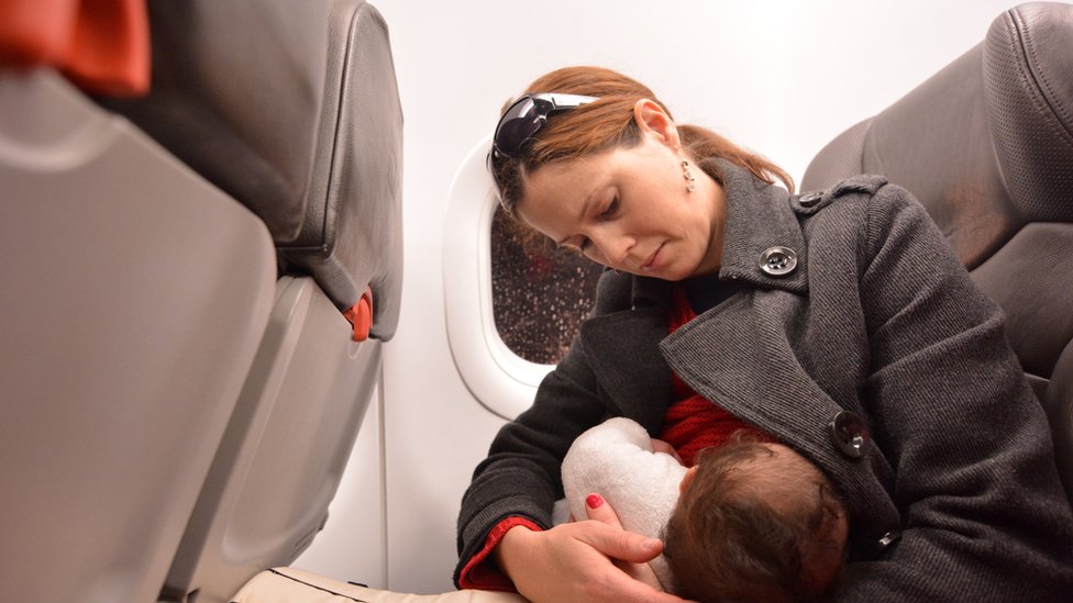 Женщина кормит ребенка грудью в самолете