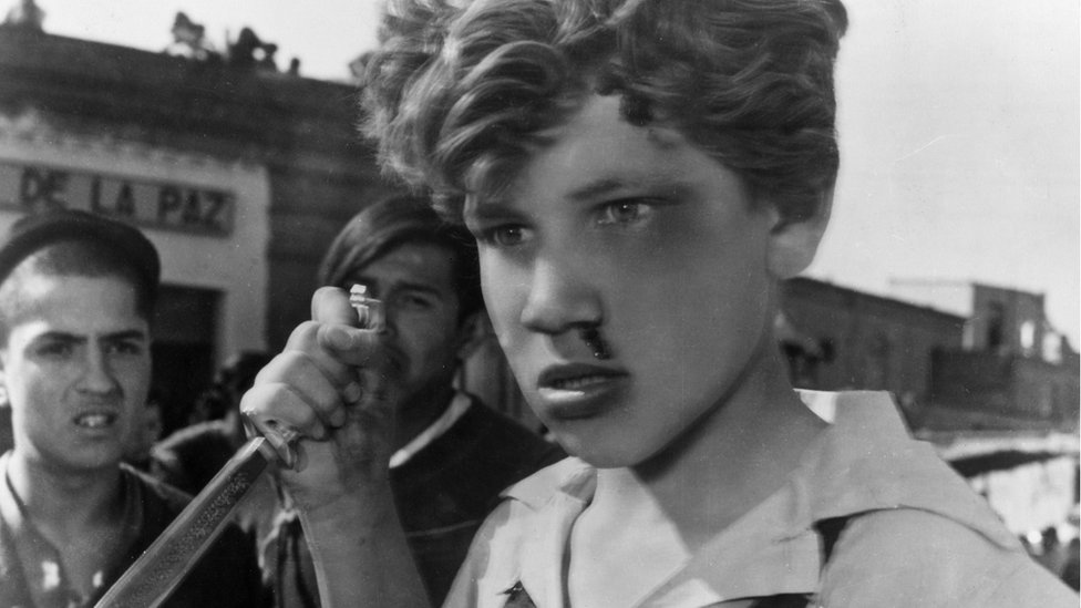 Escena de "Los olvidados": un joven con la nariz ensangrentada amenaza con un puñal.