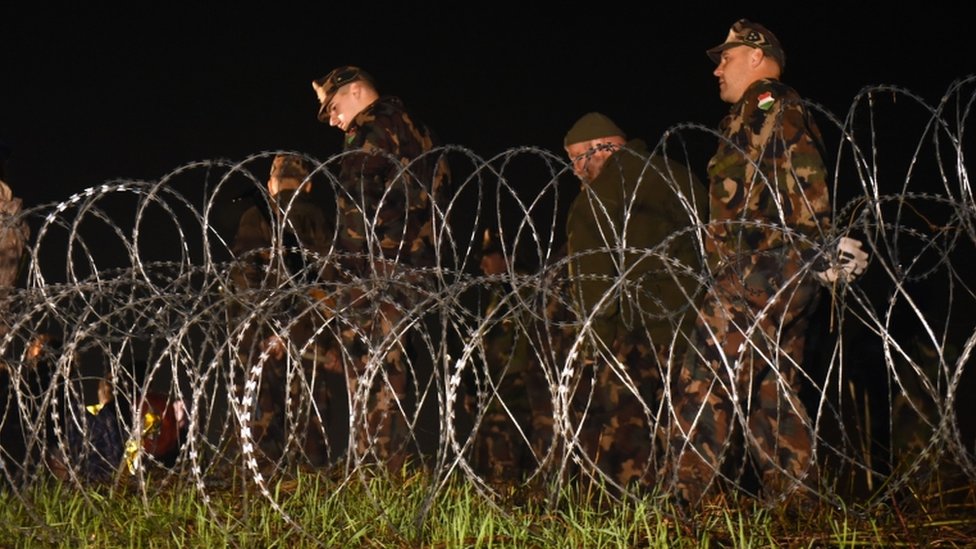 Венгерская полиция и солдаты закрывают границу между Венгрией и Хорватией колючей проволокой и забором в Ботово, 16 октября 2015 года.