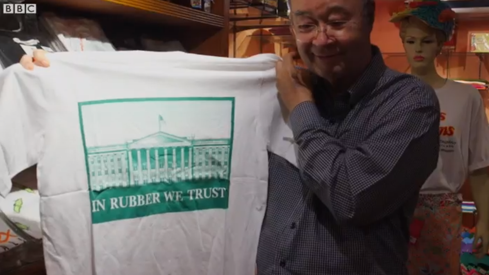 "Confiamos en la goma", dice el eslogan en inglés de esta camiseta que parodia el lema nacional oficial de Estados Unidos "In God we trust". Michai Viravaidya, el "Rey de los condones" de Tailandia, agarrando una camiseta