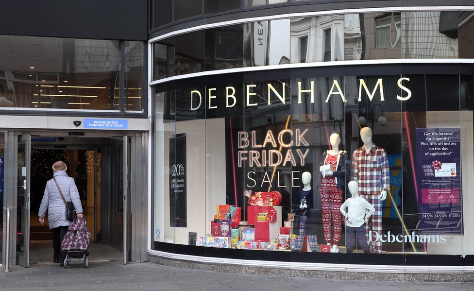 Женщина проходит мимо окна магазина Debenhams в Белфасте