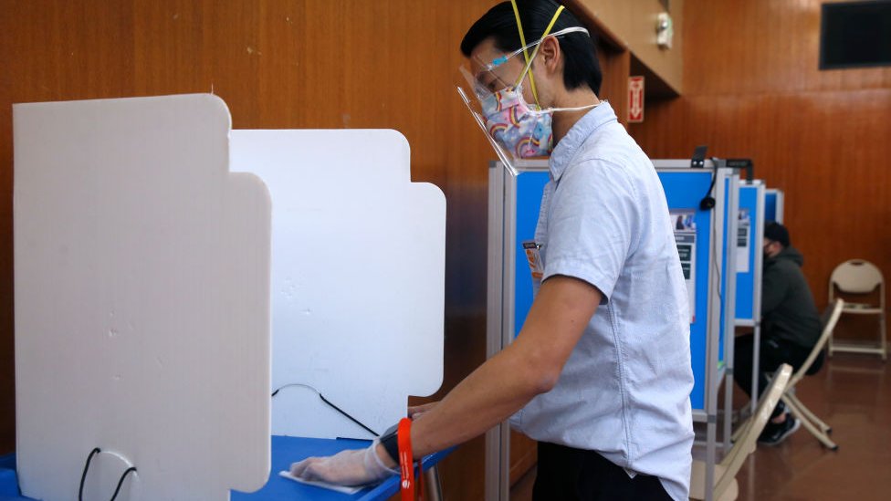 Hombre votando con mascarilla facial.
