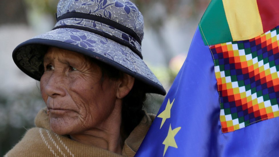 Una mujer sostiene la bandera marítima de Bolivia.