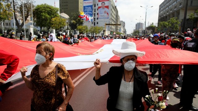 Personas llevan una bandera enorme de Perú por el centro de Lima