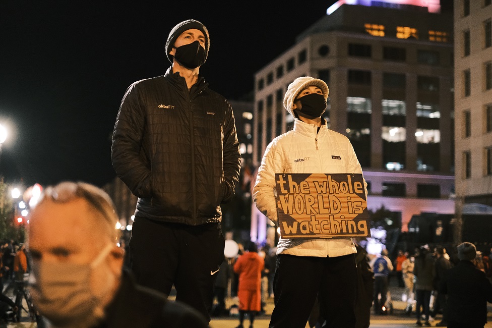 A person holds a sign that reads 