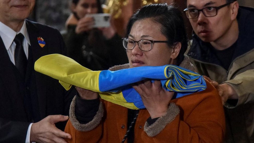 A mãe de Jonathan Tseng segura uma bandeira da Ucrânia