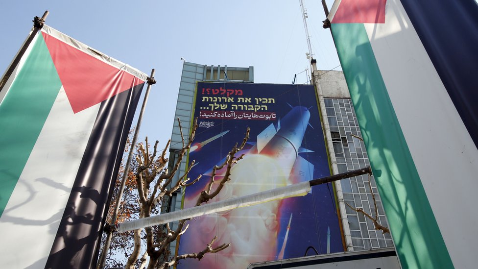 Palestinian flags and a billboard depicting Iranian missiles with a message in Persian and Hebrew reading "prepare your coffins" hangs on a building at Palestine Square in Tehran, Iran (16 January 2024)