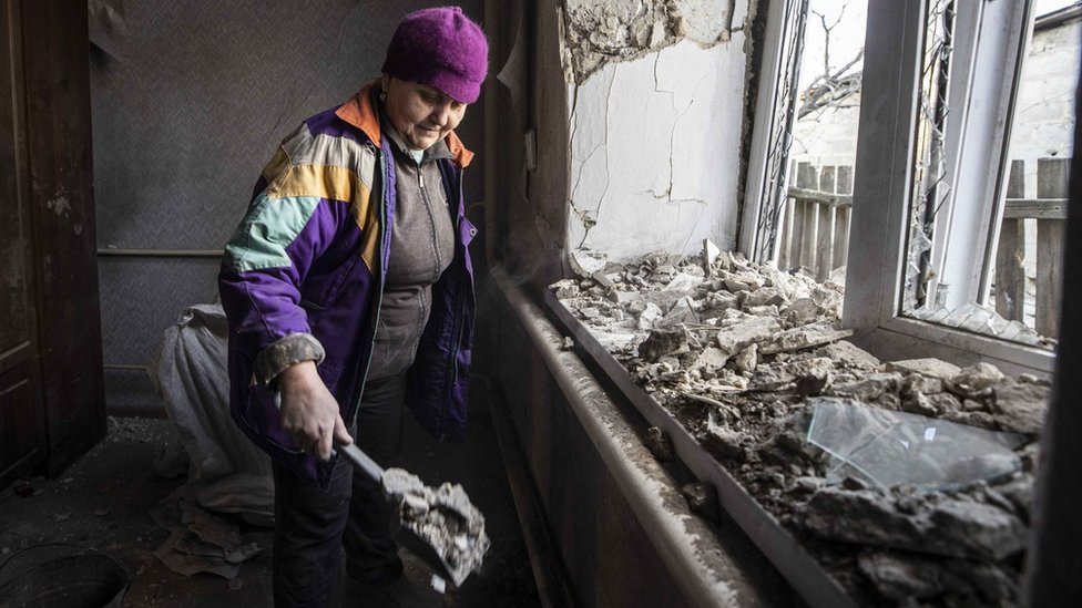 在俄羅斯支持的叛軍控制的頓涅茨克地區，一名婦女在炮火過後清理被破壞的房屋