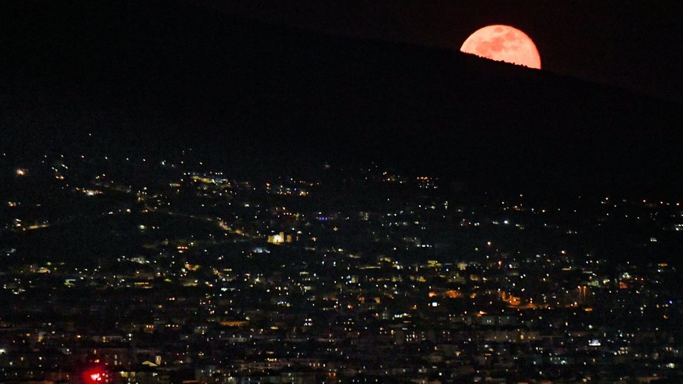 The red supermoon rises behind Mt Vesuvius as seen from Naples, Italy