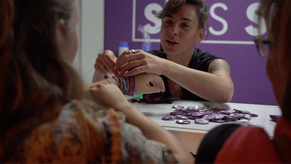 Staff at an information stand speaking to young people.