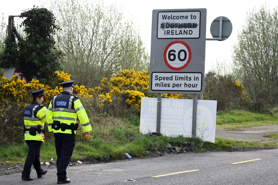Офицеры полиции Ирландии идут по дороге, которая пересекает границу между Республикой Ирландия и Северной Ирландией