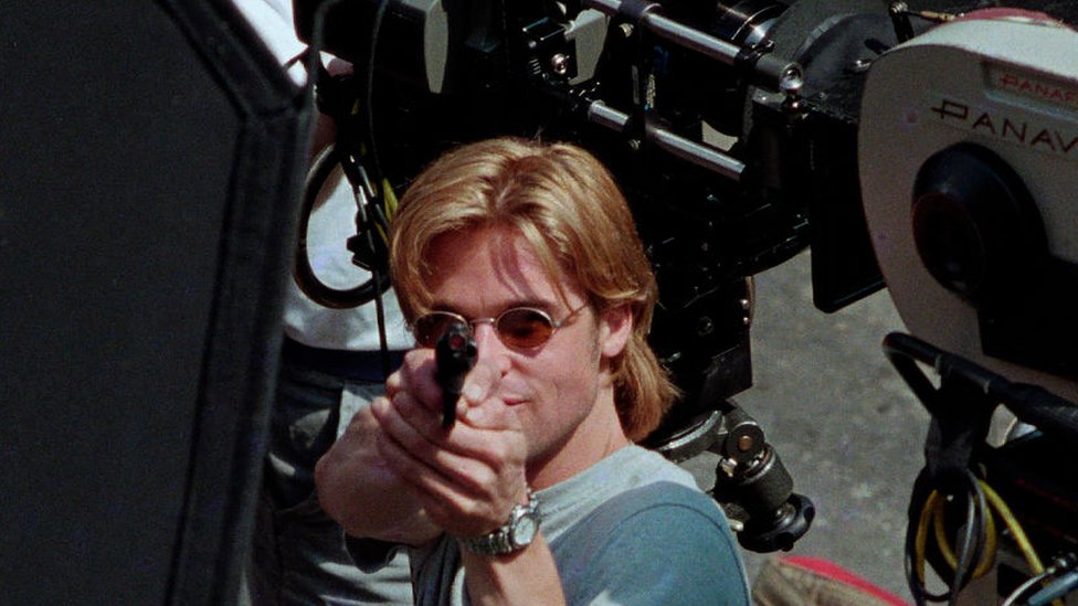 Brad Pitt aims a gun in a film