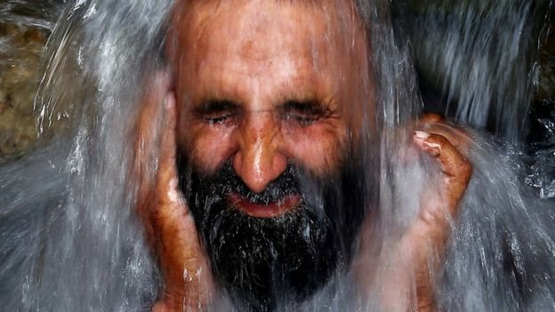 Hombre refrescándose con agua durante una ola de calor en Pakistán