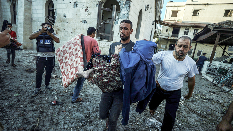 An injured Palestinian is carried away from Al-Ahli Baptist Hospital after it was hit in Gaza City, Gaza on 18 October, 2023.