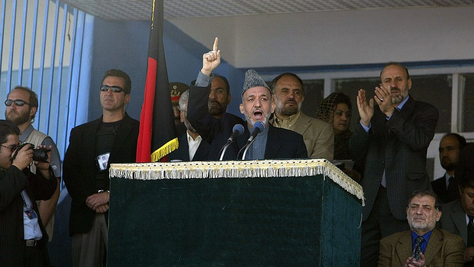 Hamid Karzai dando un discurso rodeado de personas.