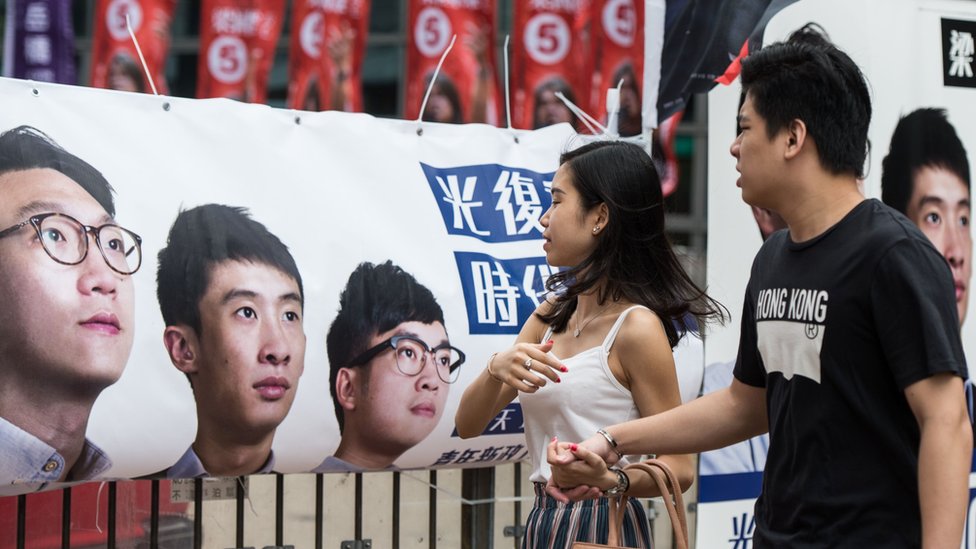 Пешеходы проходят мимо плаката новой партии Youngspiration с изображением дисквалифицированных кандидатов Эдварда Люна (слева) и Баджо Люна (справа) во время выборов в Законодательный совет в Гонконге 4 сентября 2016 г.