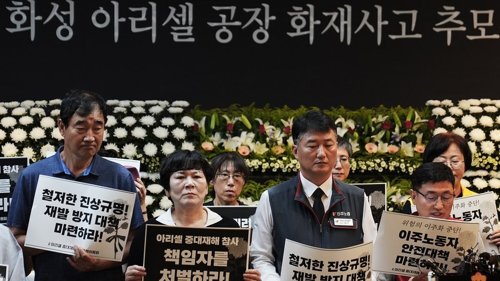 韓國勞工組織的維權人士在市政廳舉牌，要求廠方及政府負責補償受害者家庭，更好地保護外來移工權益。
