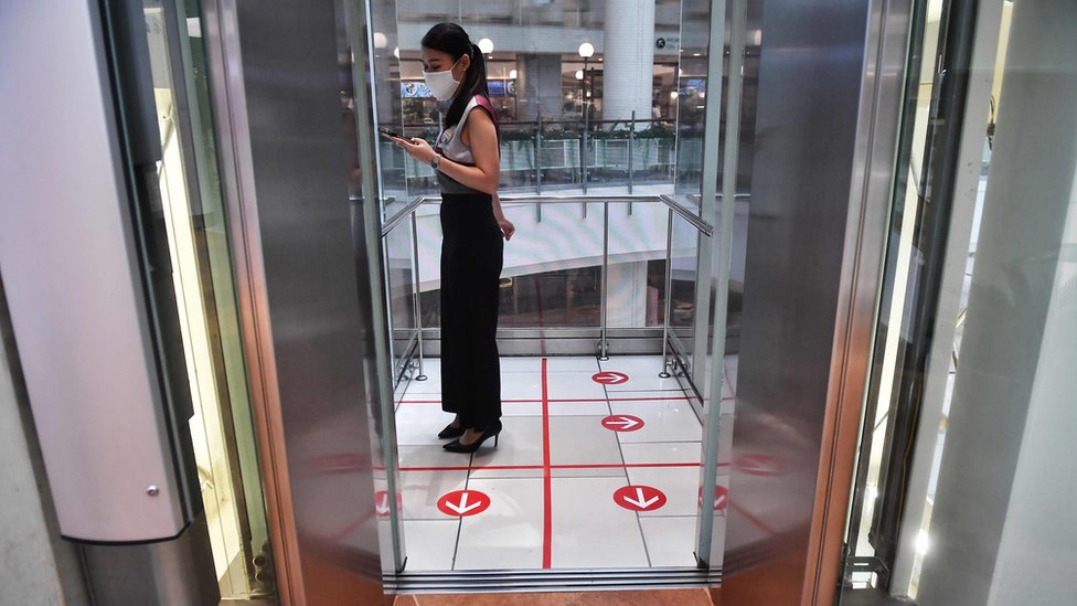 A woman stands in an elevator with markers on the floor for social distancing measures in a shopping mall amid concerns over the spread of the COVID-19 coronavirus in Bangkok on March 20, 2020