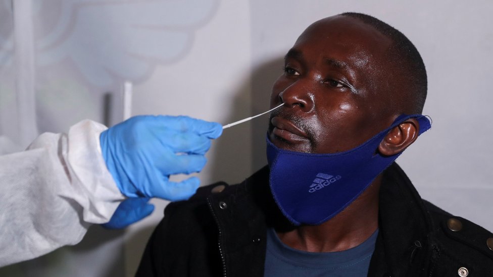 A healthcare worker collects a swab from a passenger at O.R. Tambo International Airport in Johannesburg, South Africa,