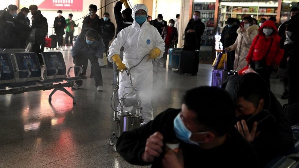 在中國安徽省合肥市火車站，身穿新冠病毒防護服的工作人員對火車站出發區進行消毒（2020年3月4日資料照片）。