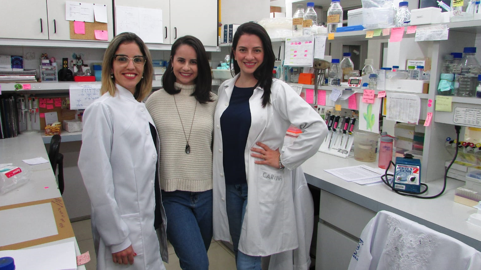 Luana Moraes, Jamile Ramos da Silva e Bruna Porchia posam para foto abraçadas e sorrindo em laboratório