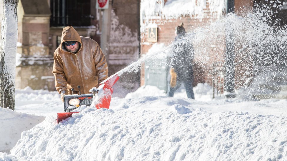 رجل يزيل الثلج المتراكم أمام بيته في بوسطن